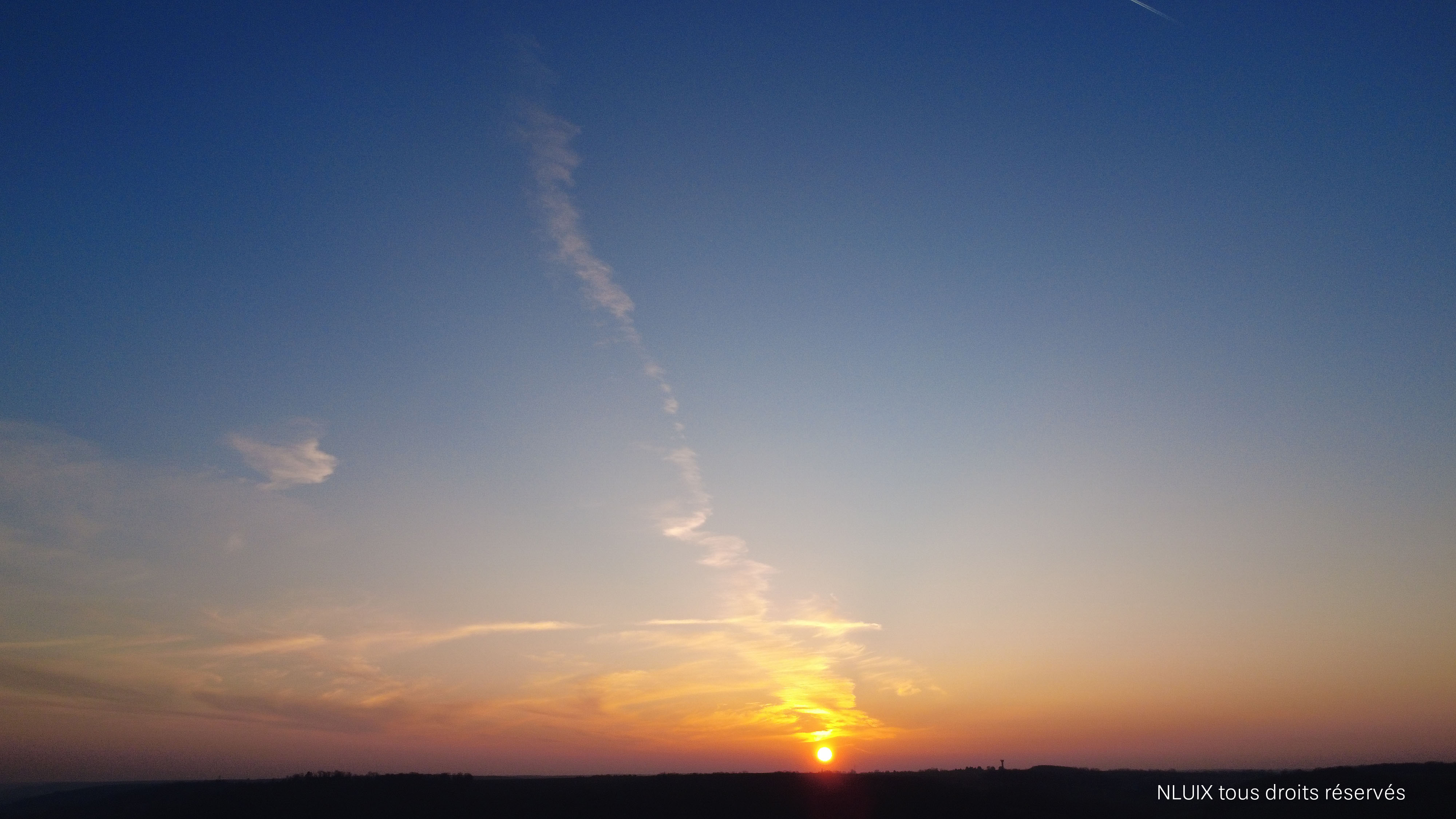 Un couché de soleil, la ligne d'horizon sombre laisse entrer le solei tel un biscuit.